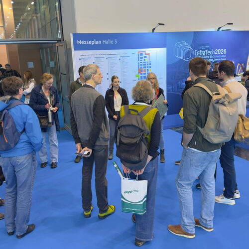 Eine Gruppe aus Menschen, die in einem Kreis stehen und gespannt einer Person zuhören