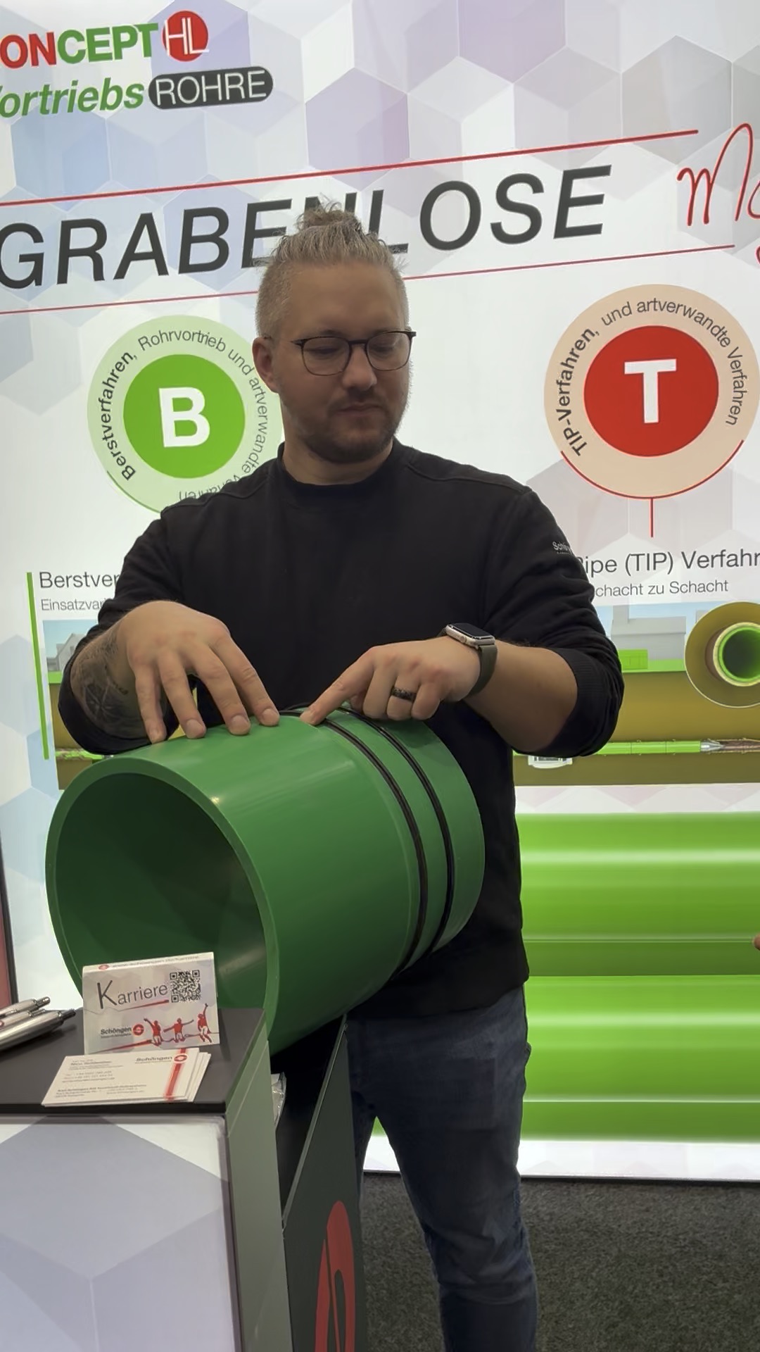 Mann zeigt grünes Kunststoffrohr